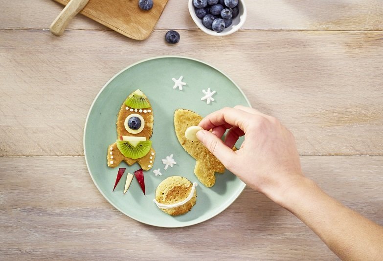 Pancakes für Kinder werden mit Früchten dekoriert.