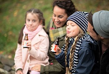 Familie trinkt Rotbäckchen Immunstar Mini bei Ausflug im Herbst.
